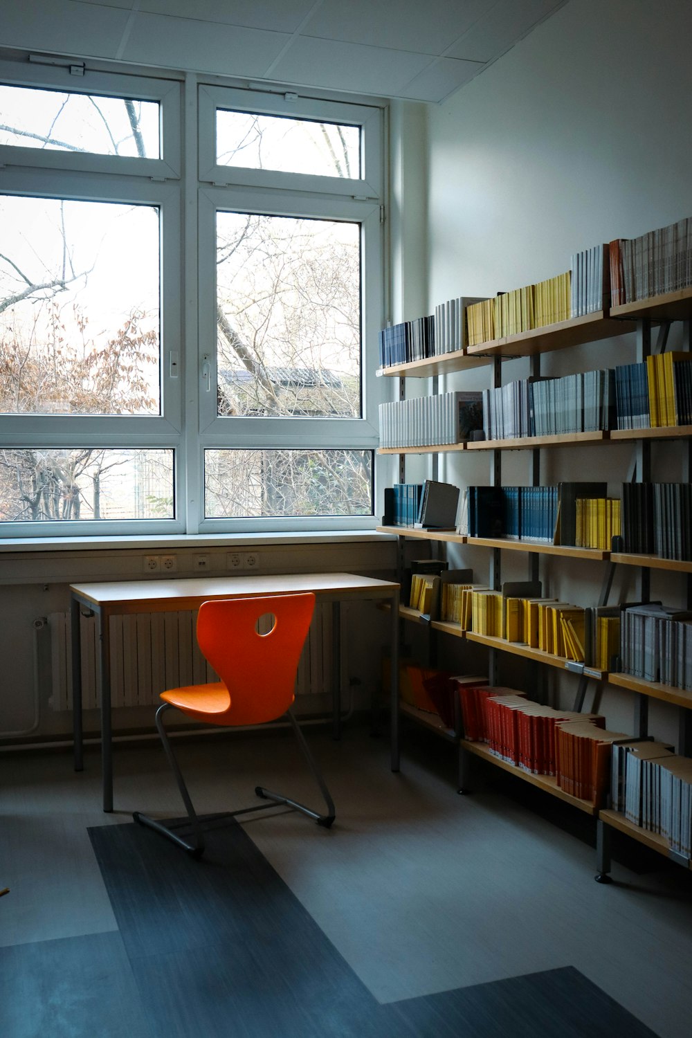 an orange chair sitting in front of a book shelf
