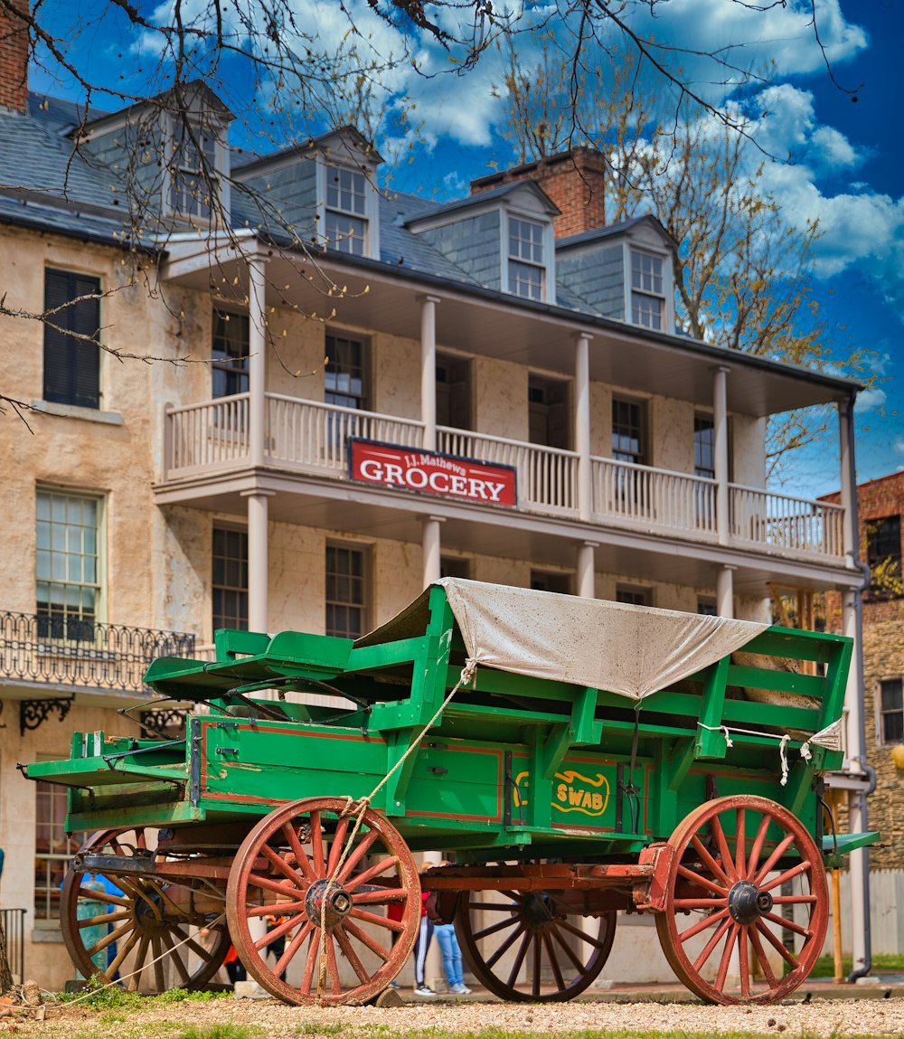 a green horse drawn carriage parked in front of a building