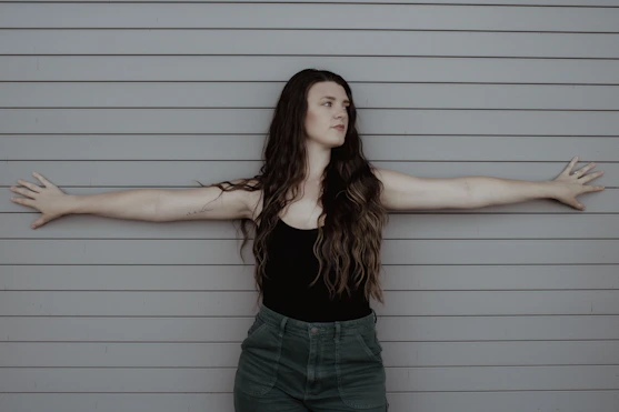 a woman standing in front of a wall with her arms outstretched