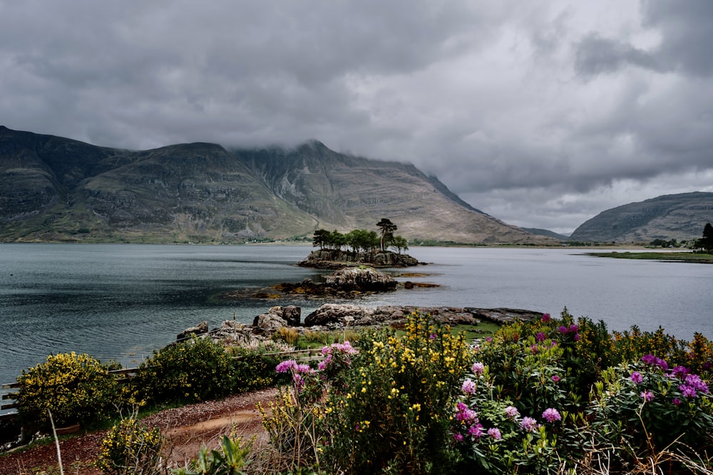 a body of water surrounded by mountains under a cloudy sky