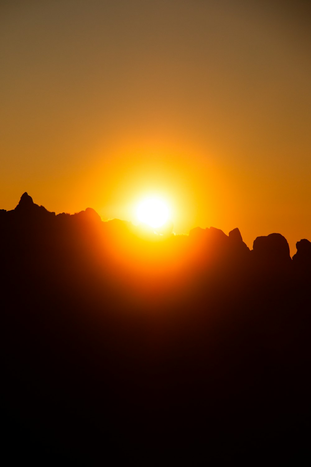 the sun is setting over a mountain range