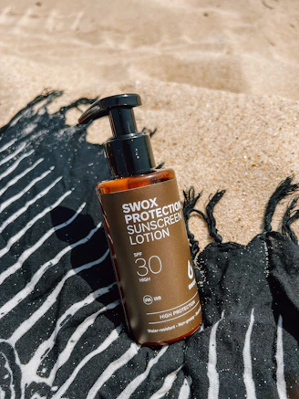 A bottle of sunscreen lotion sitting on a towel