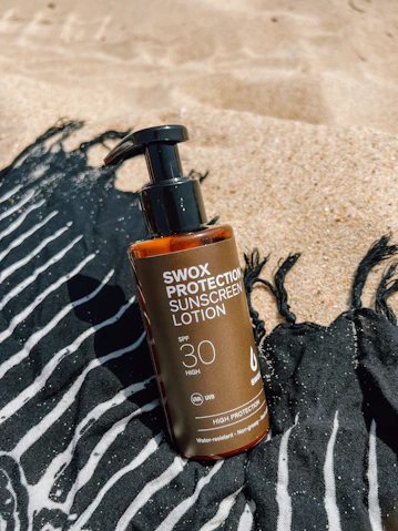 A bottle of sunscreen lotion sitting on a towel