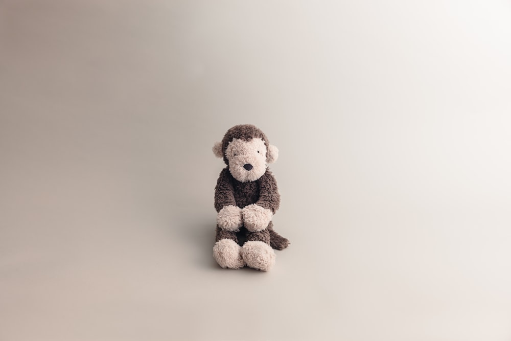 a stuffed monkey sitting on a white surface