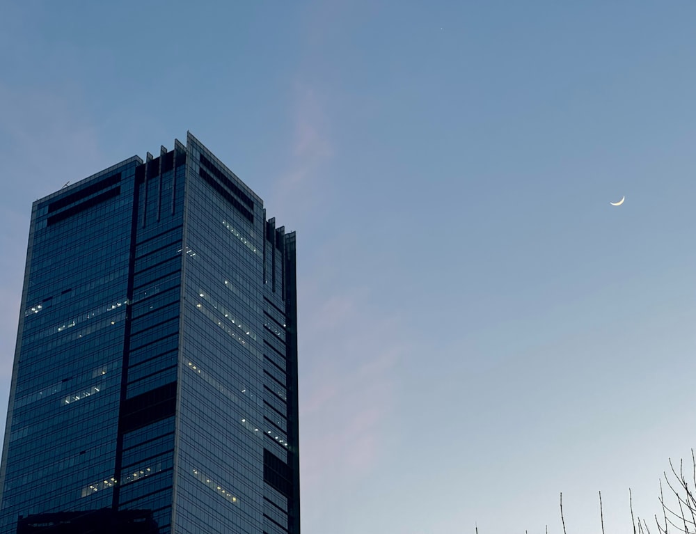 a very tall building with a half moon in the sky