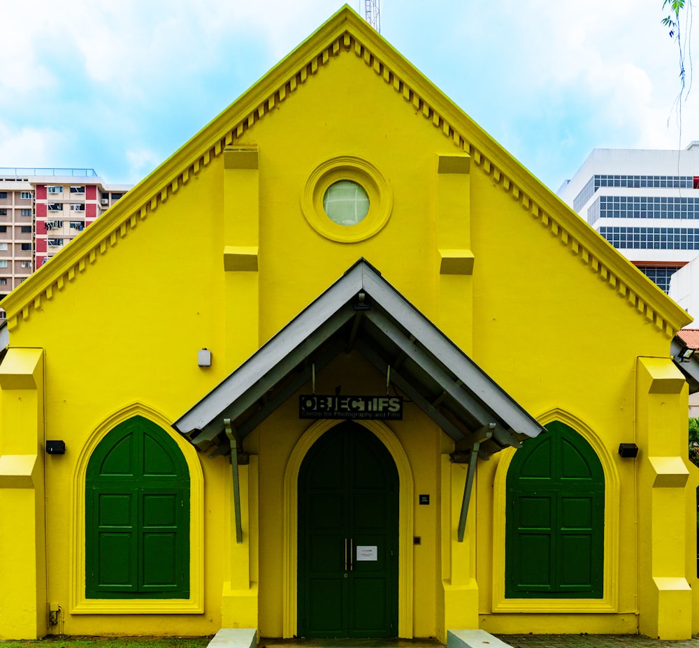 a yellow church with green doors and a clock tower