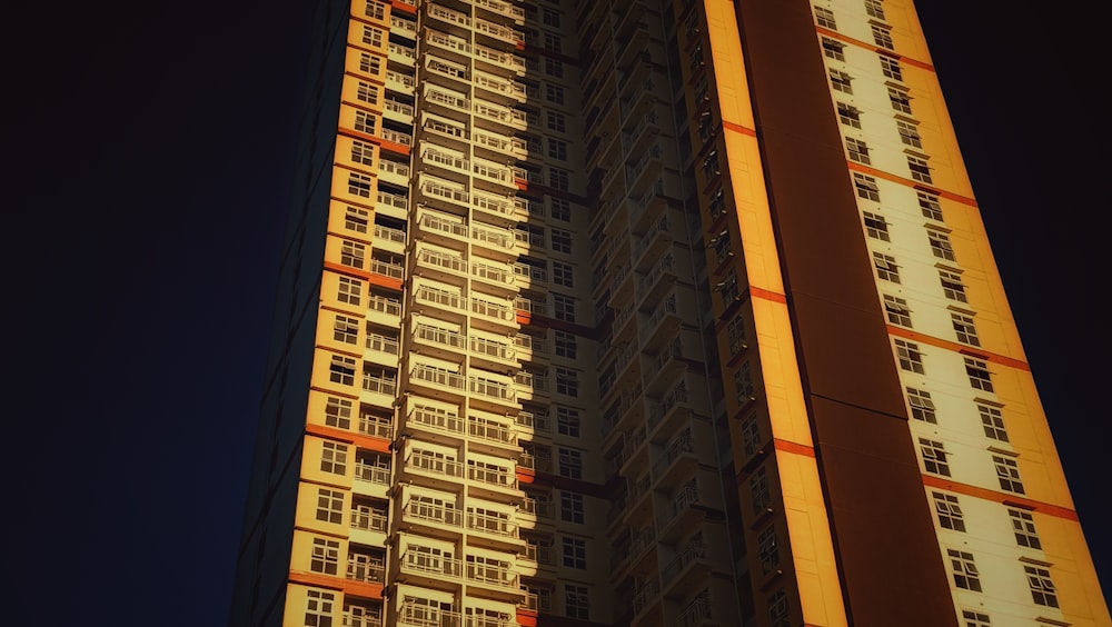 a tall building with windows and balconies against a dark sky