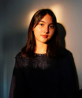a woman standing in front of a white wall
