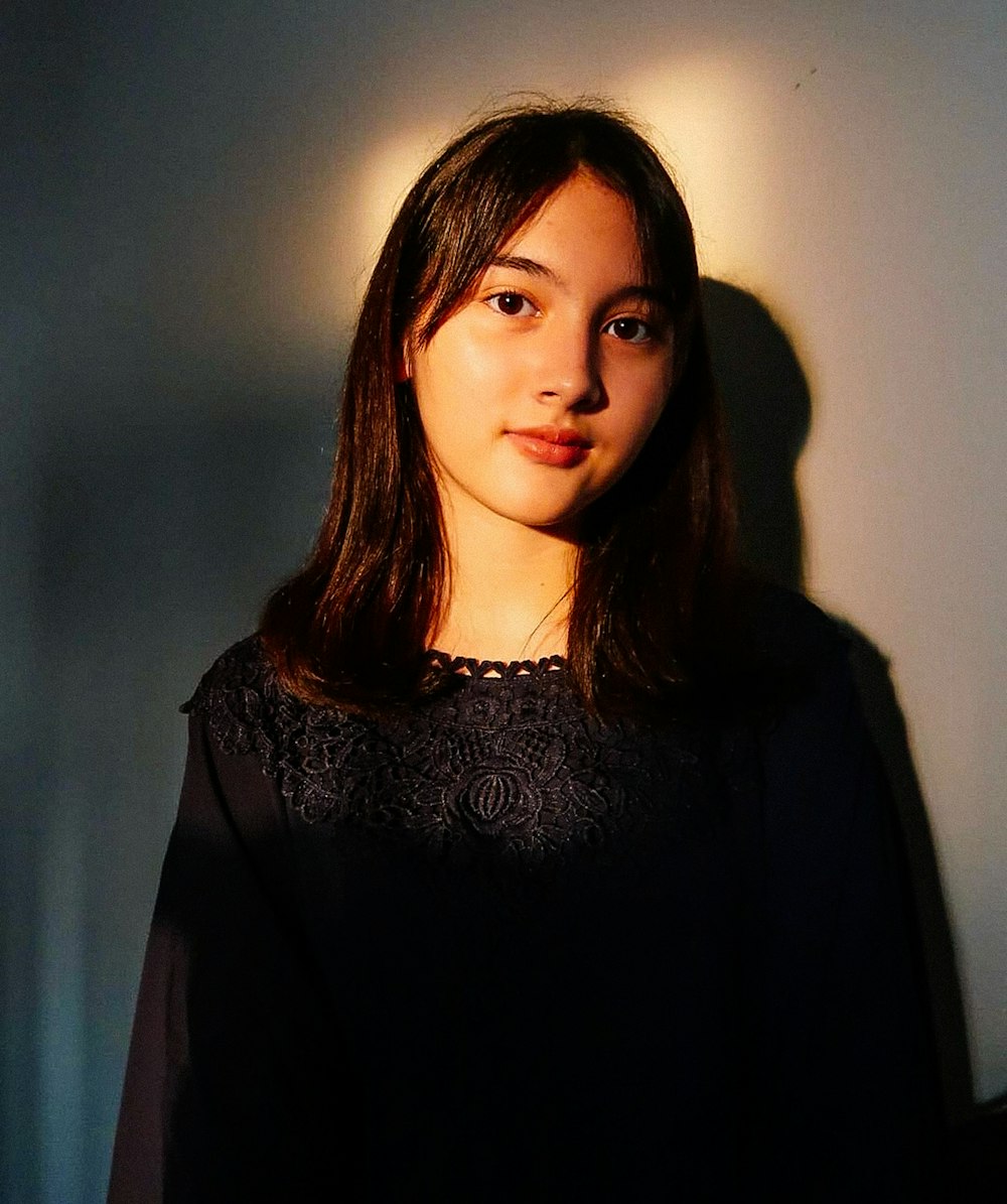 a woman standing in front of a white wall