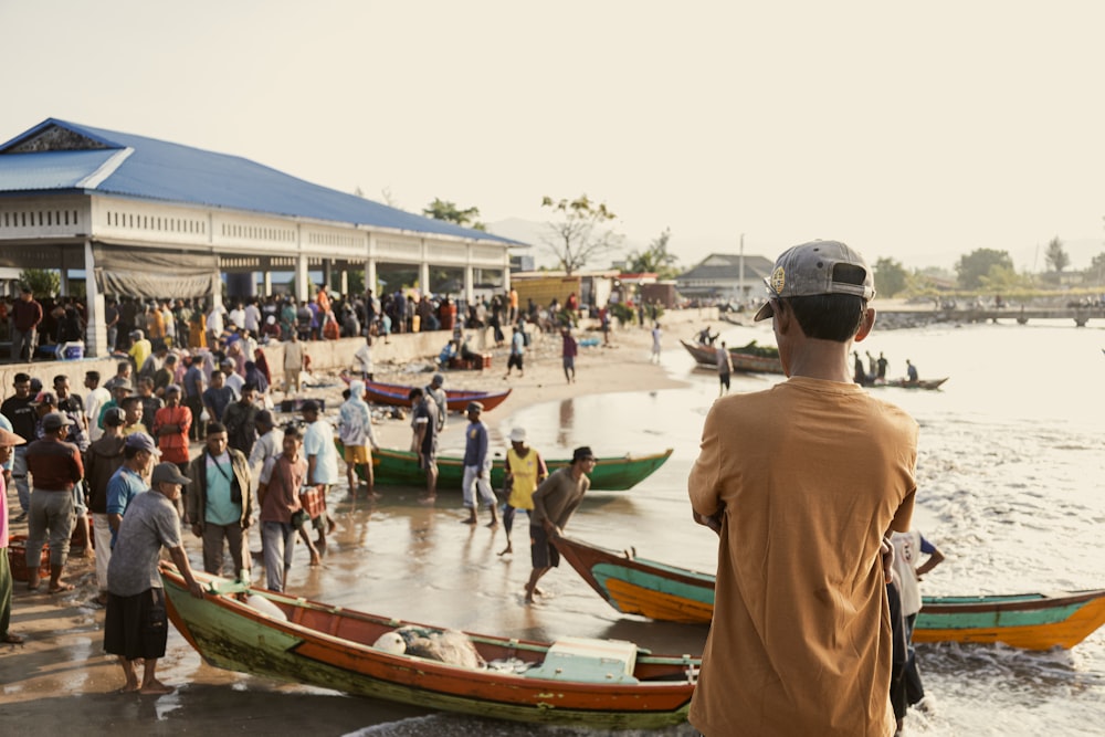 a group of people standing on a beach next to boats