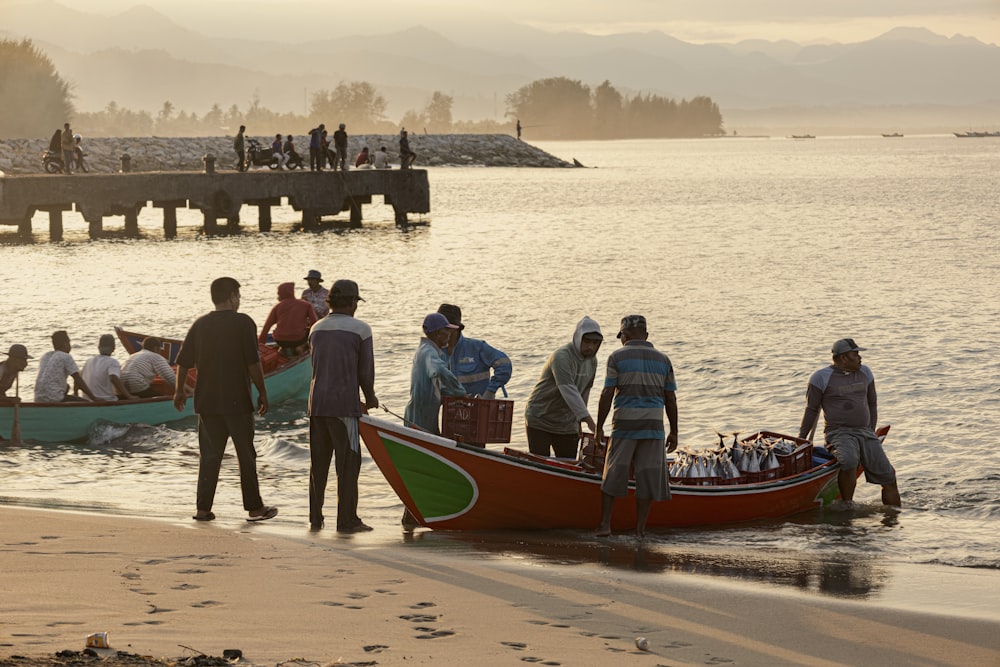 a group of people standing on the beach next to a boat