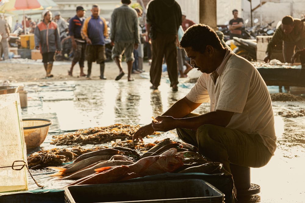 a man sitting on the ground next to a bunch of fish