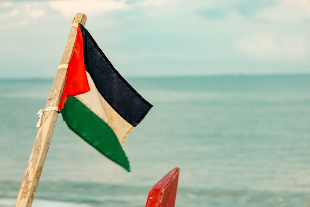 a flag on a beach next to the ocean