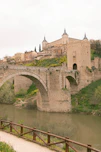 a stone bridge over a river with a castle in the background