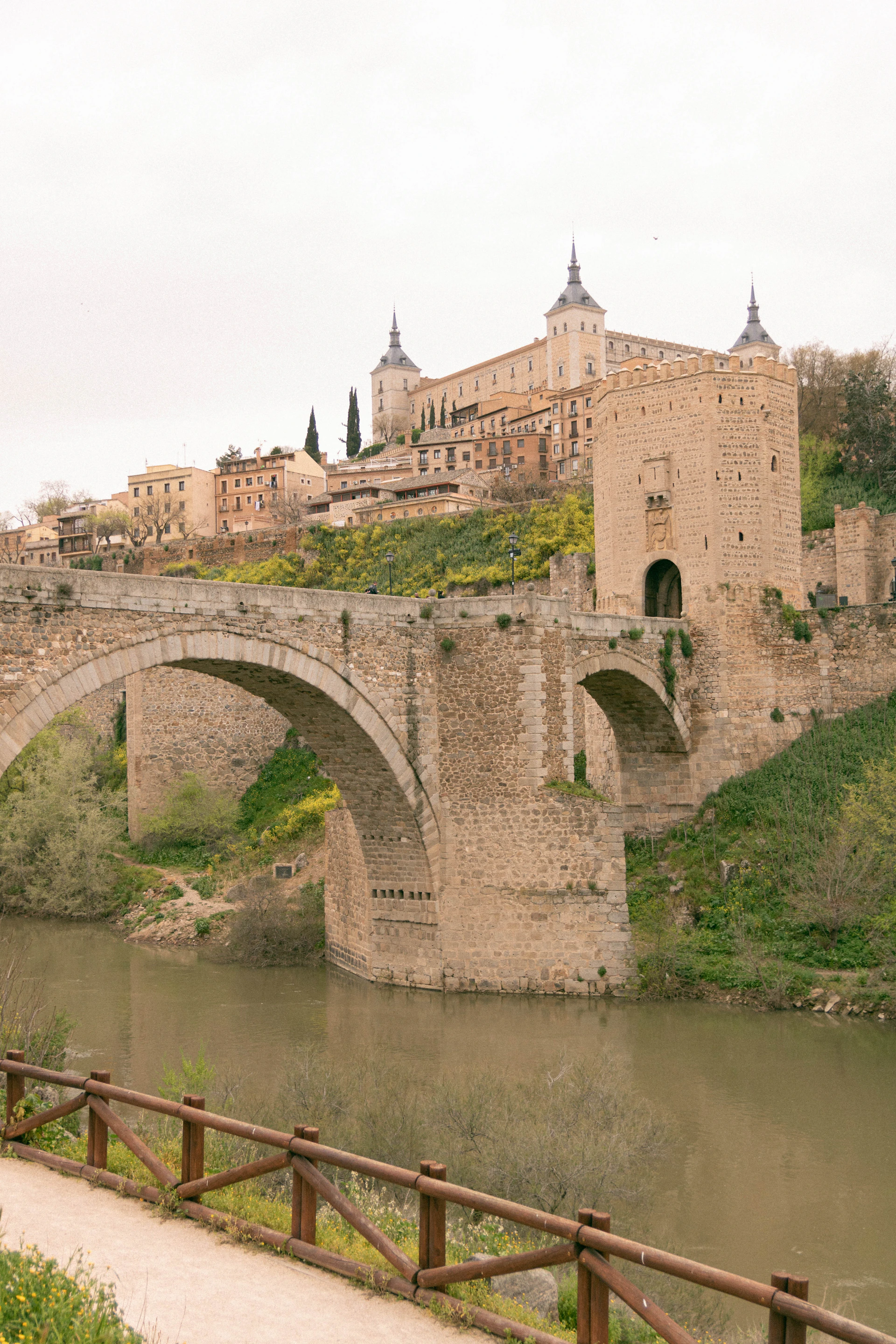 a stone bridge over a river with a castle in the background