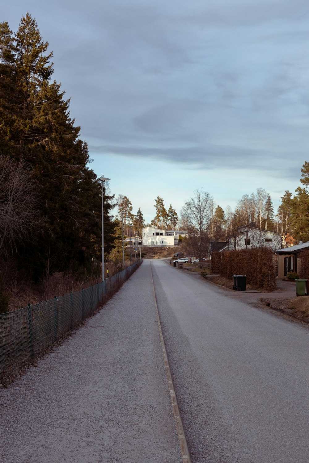 an empty street with a fence and trees in the background