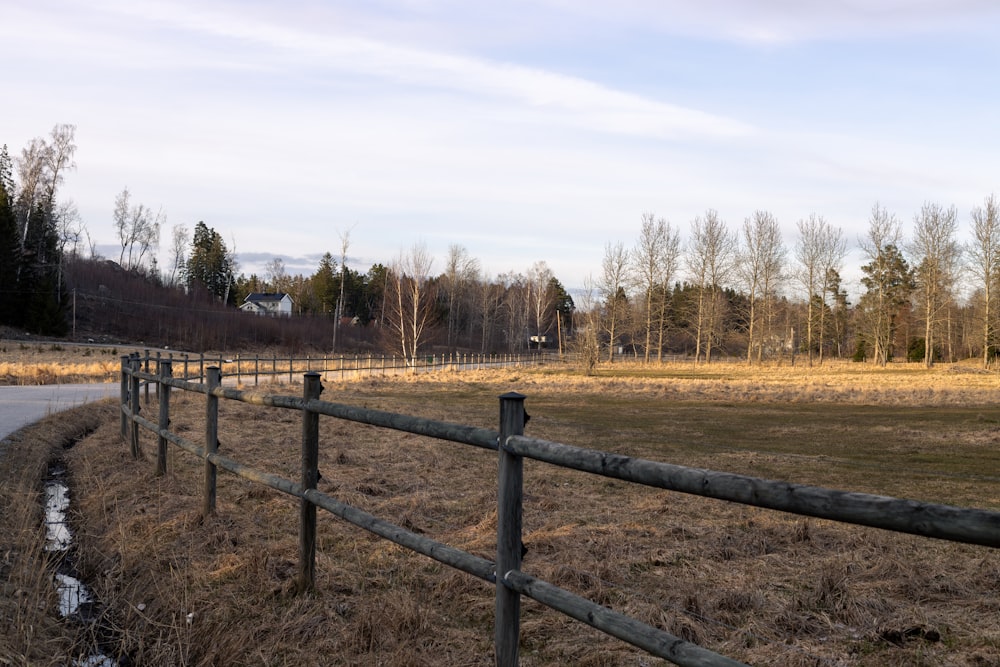 a wooden fence next to a road in a field