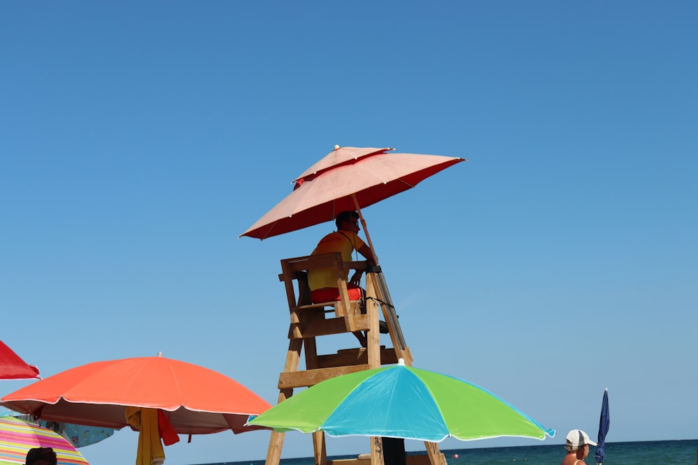 ein Rettungsschwimmerturm am Strand mit Sonnenschirmen