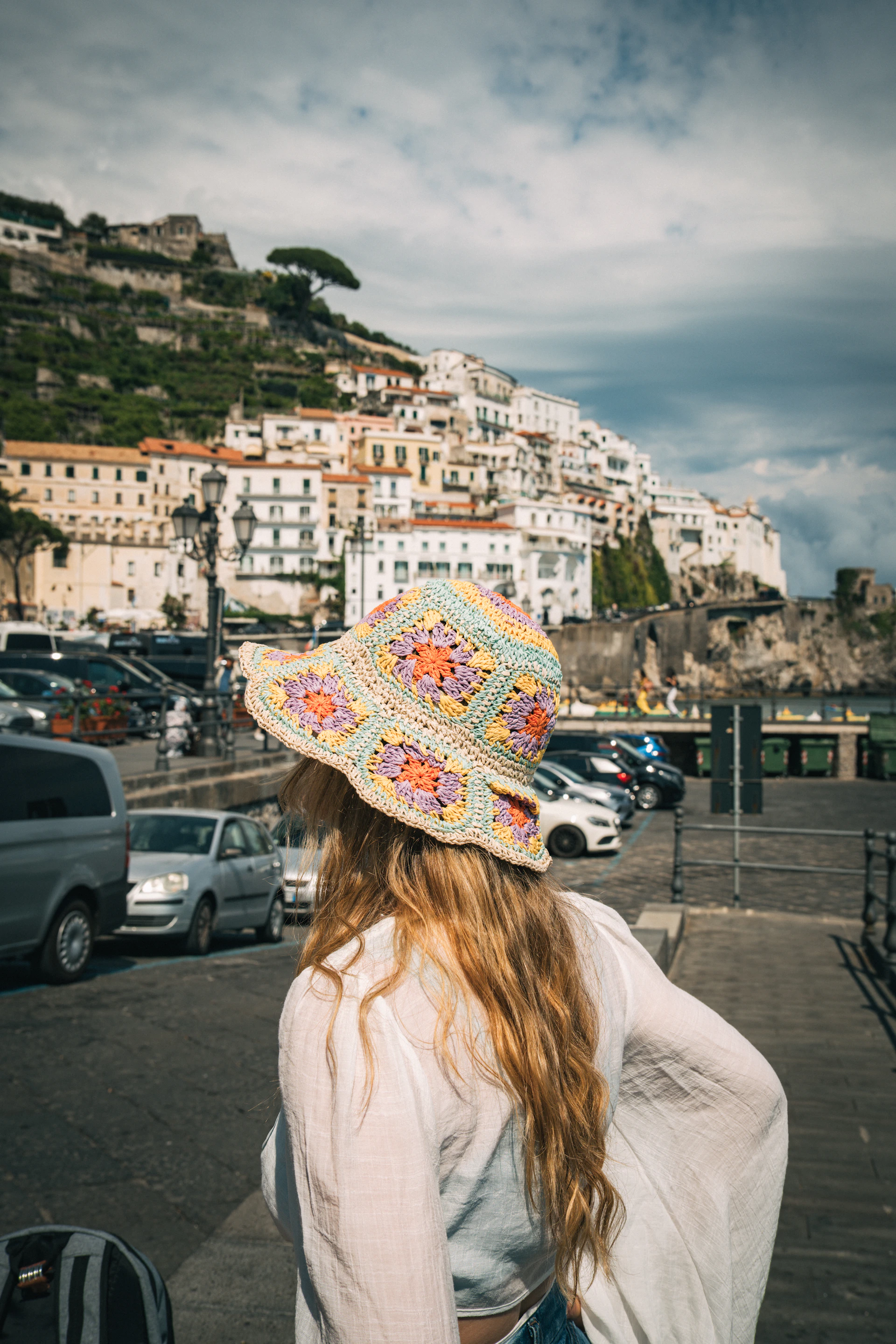 a woman wearing a hat standing in a parking lot