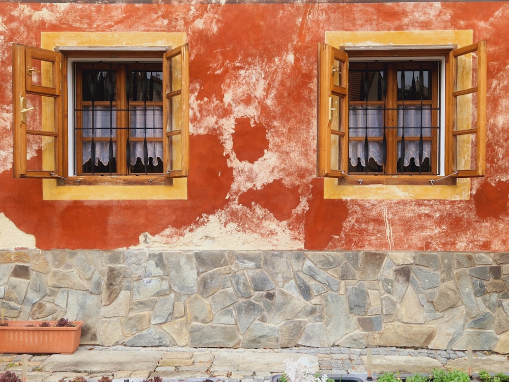 a red building with two windows and a potted plant