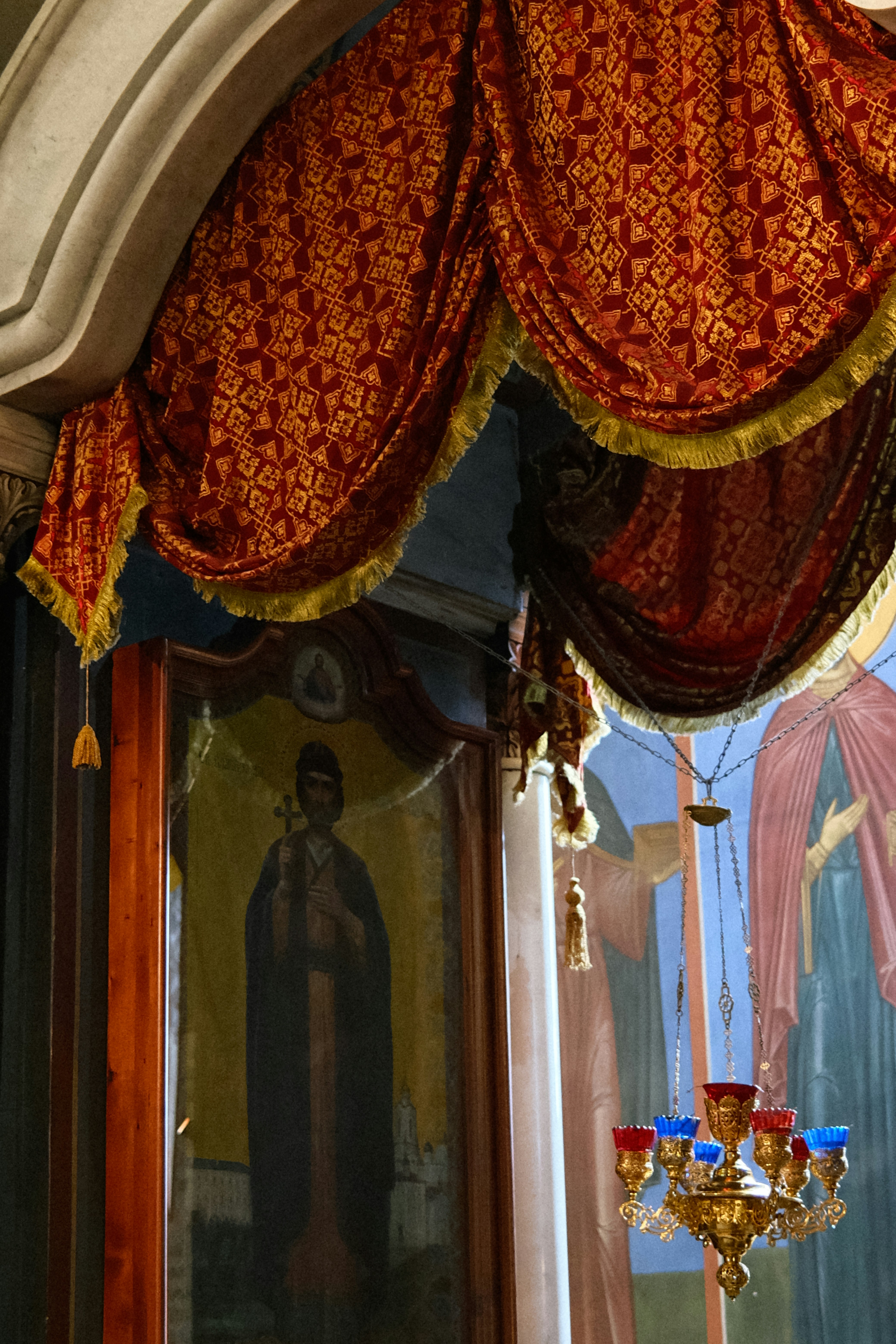 a window with a red and gold curtain and a chandelier
