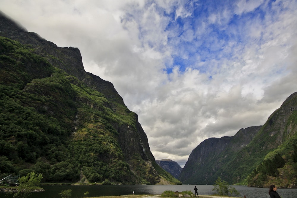 two people are standing on the shore of a lake