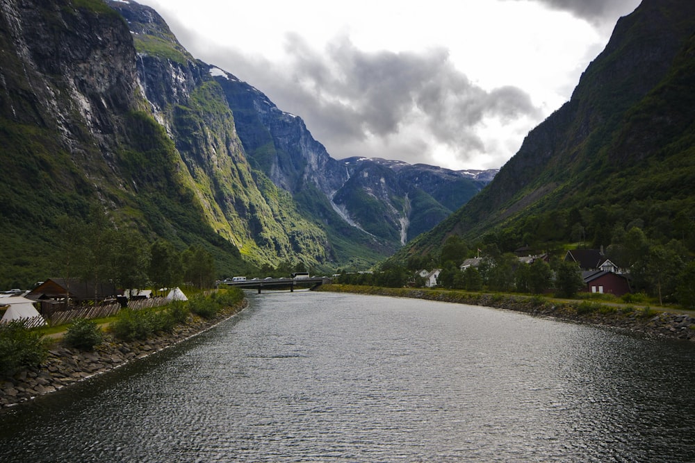 a body of water surrounded by mountains under a cloudy sky