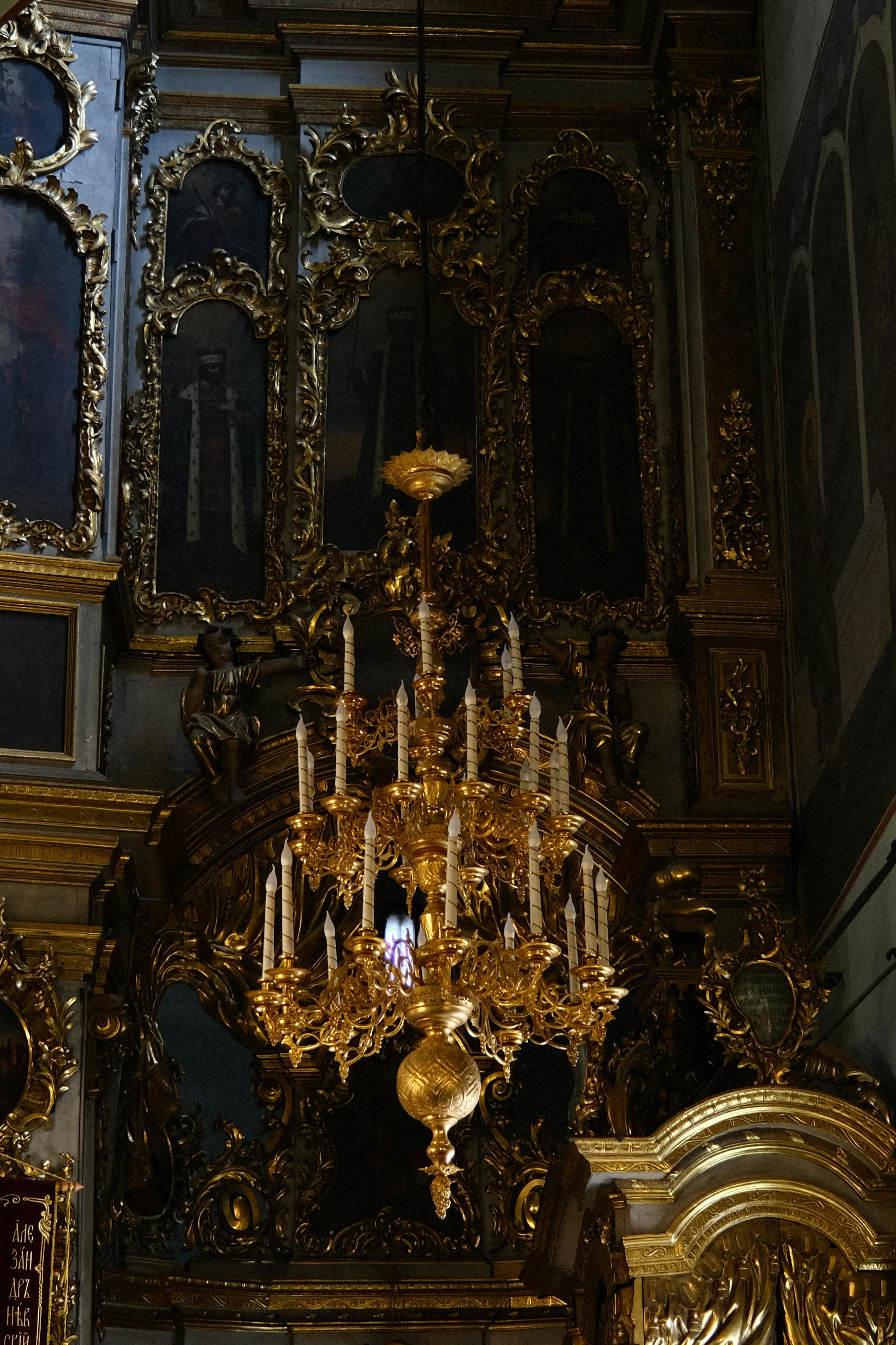 a golden chandelier in a church with paintings on the walls