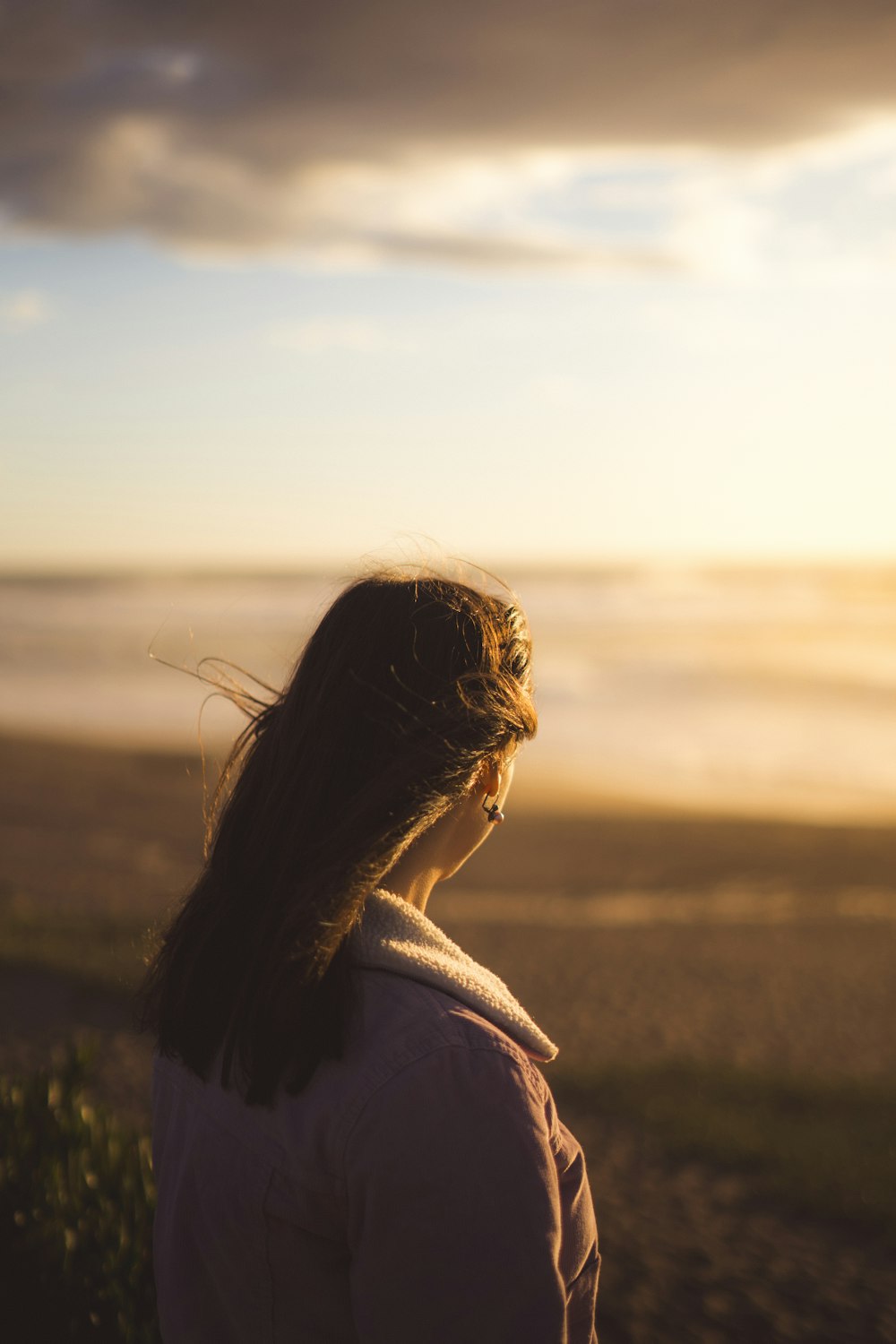 a woman standing on top of a beach next to the ocean