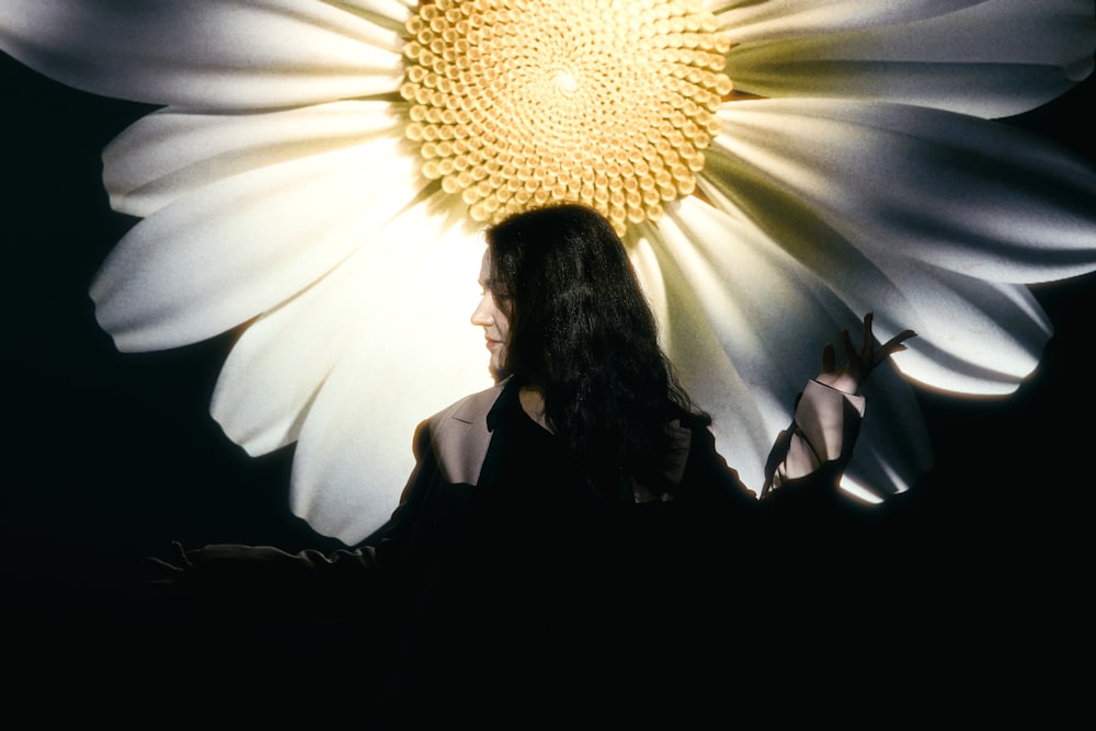 a woman standing in front of a large flower