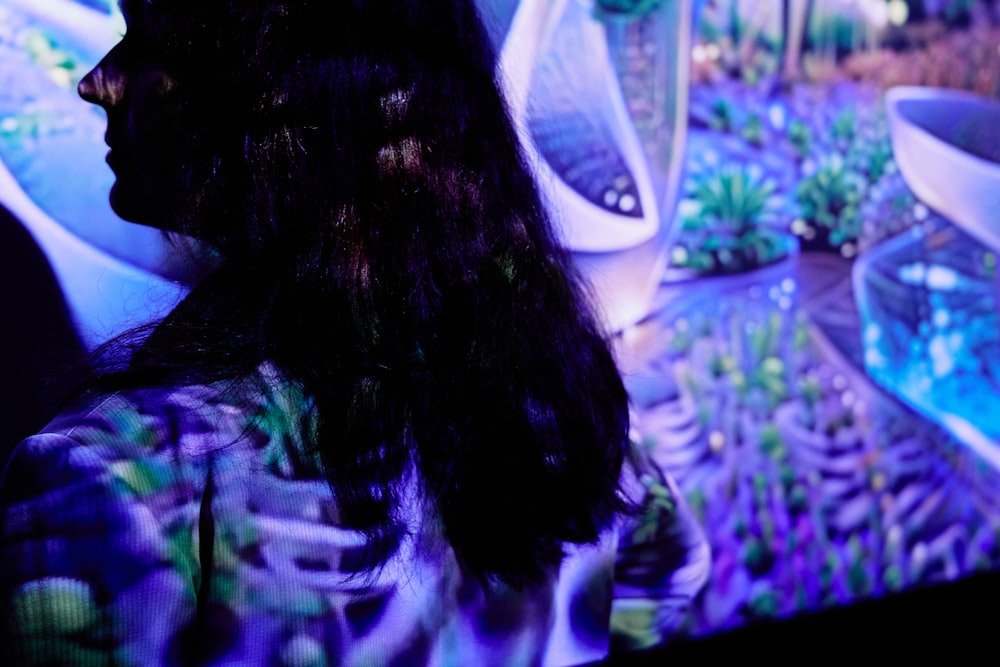 a woman standing in front of a tv with plants on it