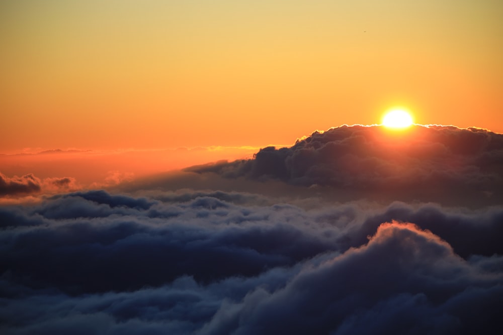 the sun is setting over the clouds in the sky