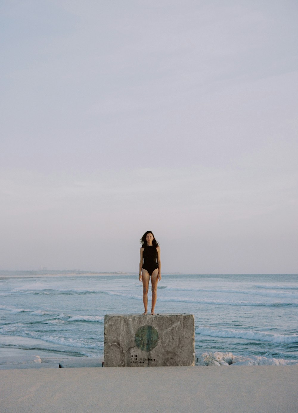 바다 근처의 돌 블록 위에 서 있는 여자
