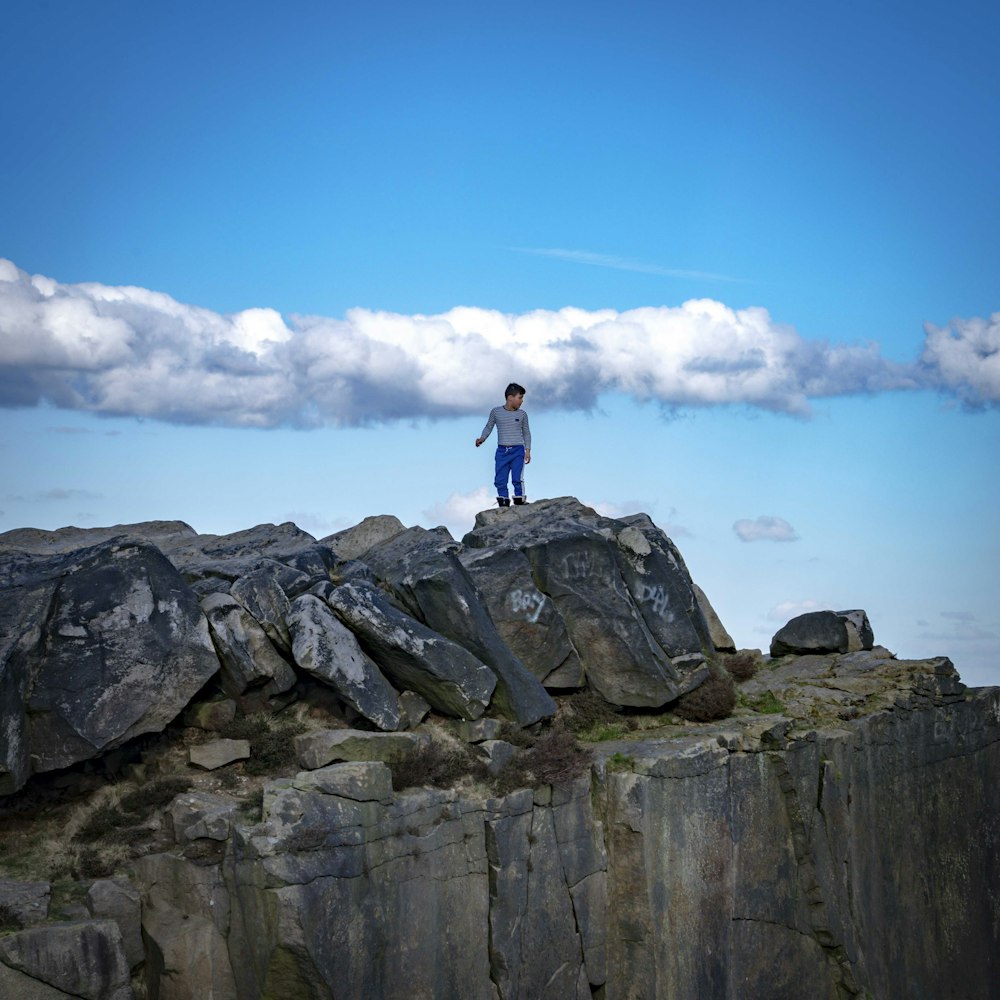 um homem em pé no topo de uma grande formação rochosa
