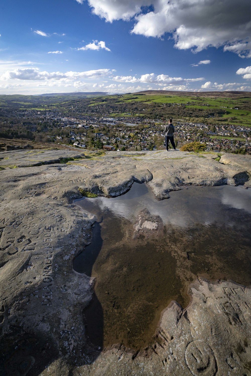 a man standing on top of a mountain next to a lake