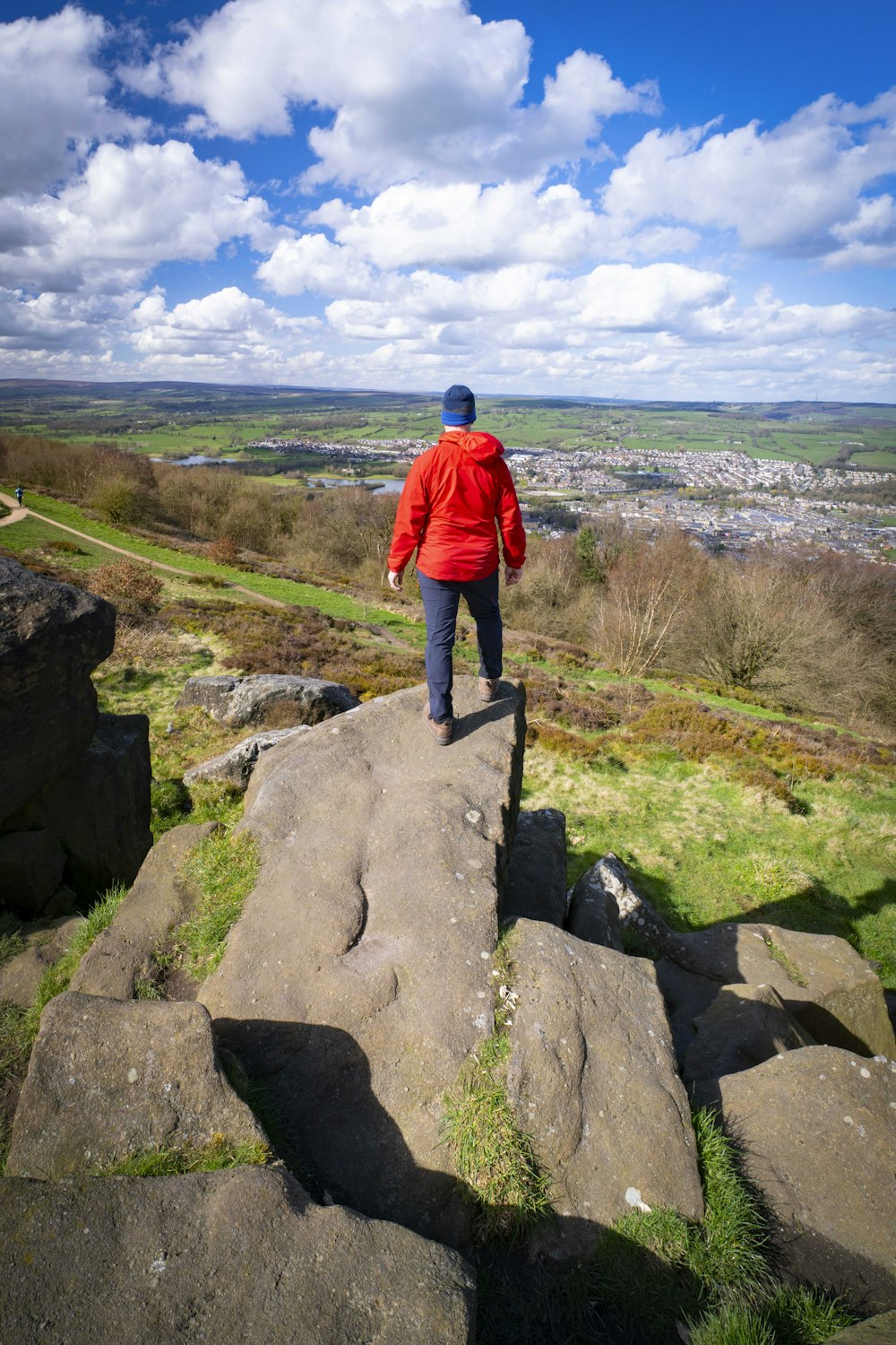 a man in a red jacket is walking on a rock