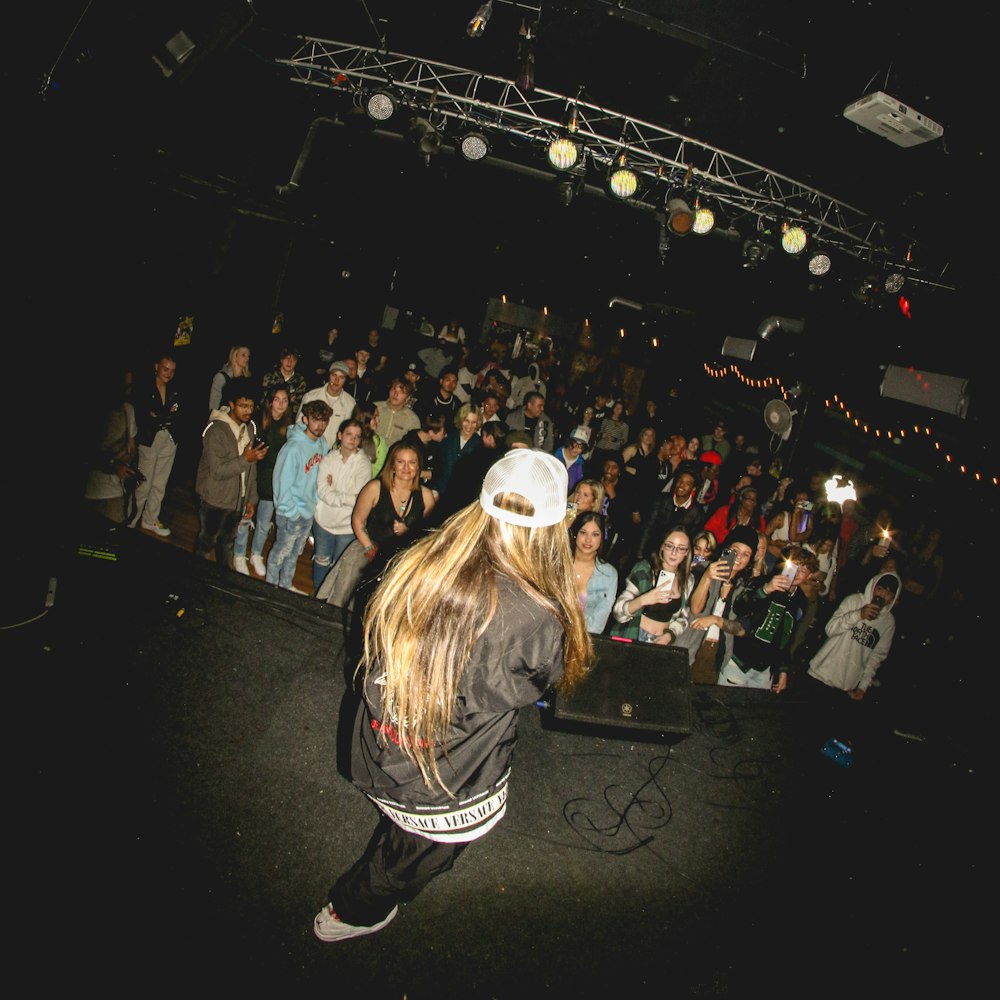 a woman in a white hat is dancing in front of a crowd