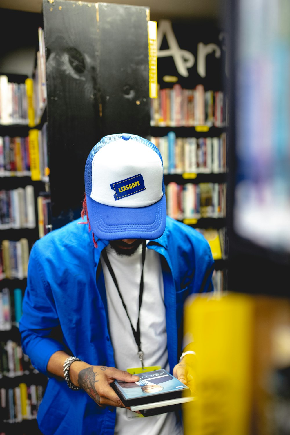 a man in a blue jacket and a white hat looking at a book