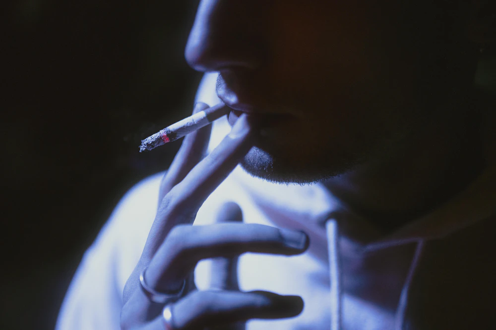 Uomo che fuma una sigaretta nel buio