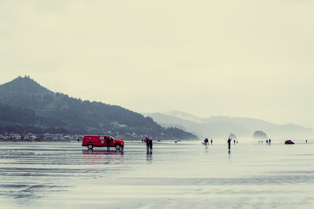 a red truck parked on top of a wet beach