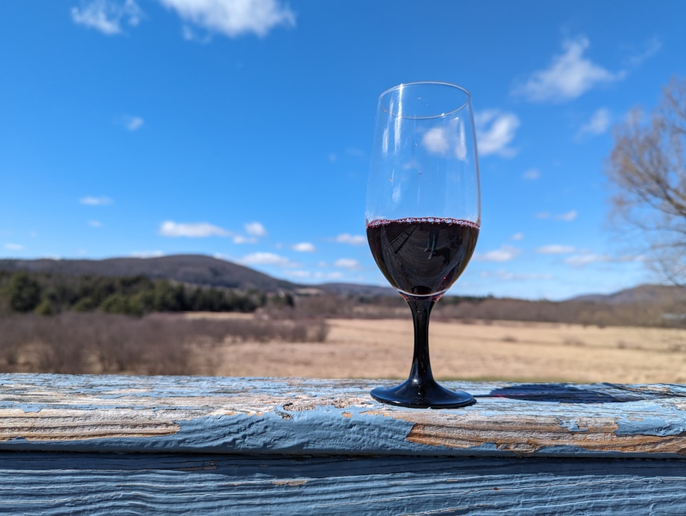 a glass of wine sitting on top of a wooden table