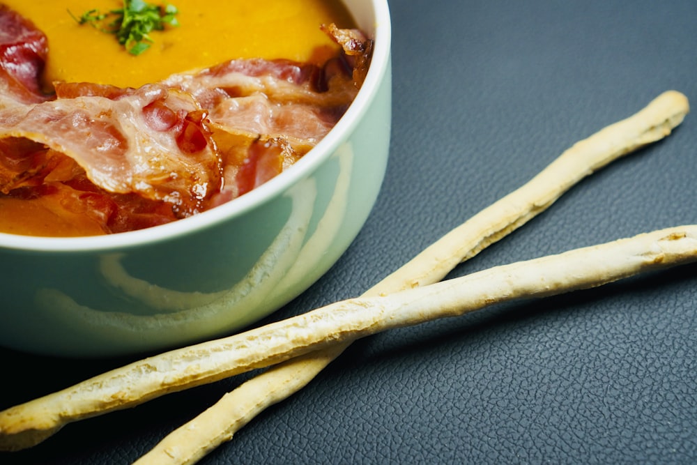 a close up of a bowl of soup and two sticks