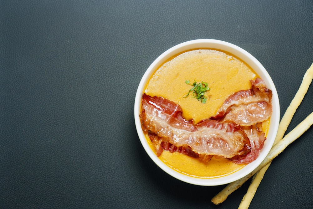 a bowl of soup with bacon on top of it