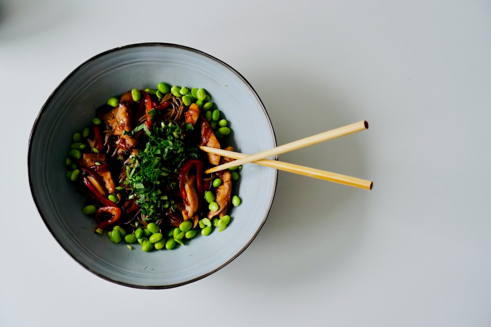 a bowl of food with chopsticks in it