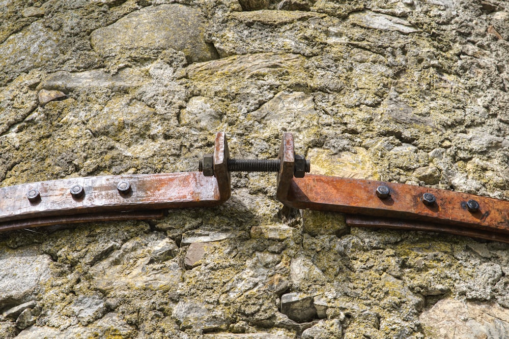 a pair of rusted metal brackets on a stone wall