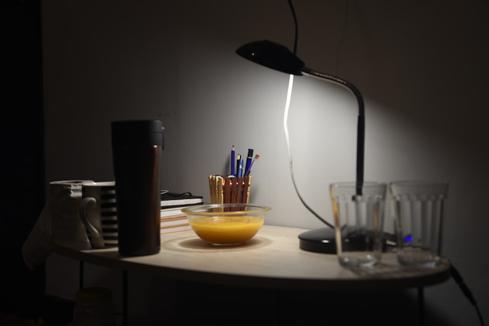 a desk with a lamp and a bowl of pens and pencils