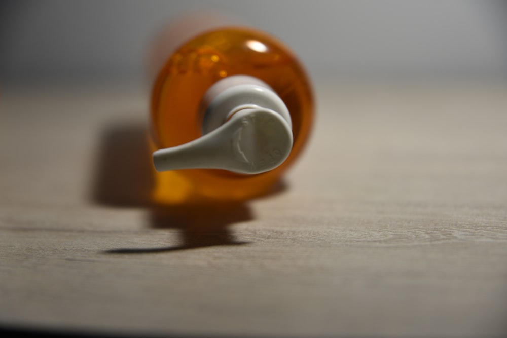 an orange bottle with a white cap on a table