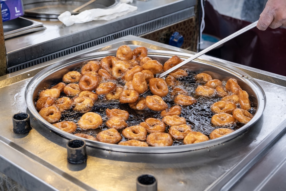 a frying pan filled with fried donuts on top of a stove
