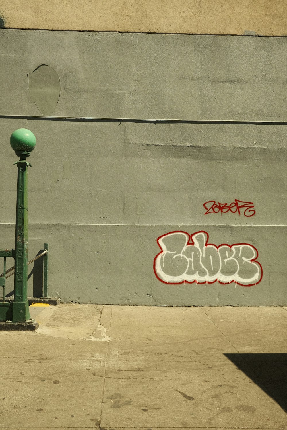 a green pole sitting next to a wall with graffiti on it