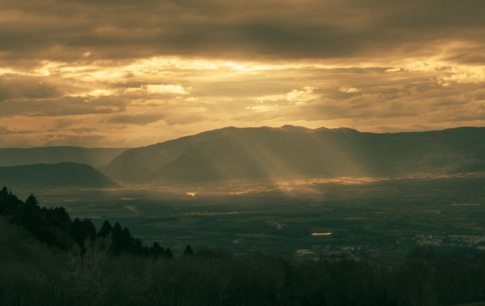 the sun is shining through the clouds over the mountains